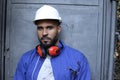 Worker wearing uniform, white hardhat and ear mufflers