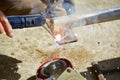 Worker with a welding machine fixing a caster wheels, fiery sparks flying around