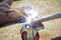 Worker with a welding machine fixing a caster wheels, fiery sparks flying around