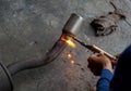 Worker welding metal exhaust pipe with sparks