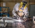 Worker welds aluminum parts. Metalworking plant, the wizard in the mask Royalty Free Stock Photo