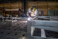 Worker welds aluminum parts. Metalworking plant, the wizard in the mask Royalty Free Stock Photo