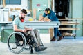 Worker in wheelchair in a carpenter`s workshop with his colleagu Royalty Free Stock Photo