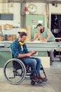 Worker in wheelchair in a carpenter`s workshop with his colleagu Royalty Free Stock Photo