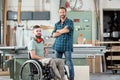 Worker in wheelchair in a carpenter`s workshop with his colleagu Royalty Free Stock Photo