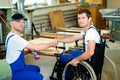 Worker in wheelchair in a carpenter's workshop with his colleagu Royalty Free Stock Photo