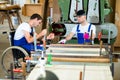 Worker in wheelchair in a carpenter's workshop with his colleagu Royalty Free Stock Photo