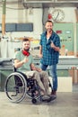 Worker in wheelchair in a carpenter`s workshop with his colleagu Royalty Free Stock Photo