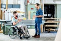 Worker in wheelchair in a carpenter`s workshop with his colleagu Royalty Free Stock Photo