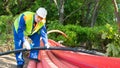 Worker in a white helmet, cuts a plastic pipe with blue scissors