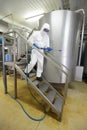 Worker in white protective uniform with high pressure washer