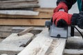 Worker whittling wood outdoor using electric planer