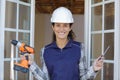 worker woman with drill and screw standing in new home