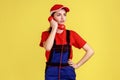 Worker woman talking on red retro phone with clients, looking away, professional service industry.