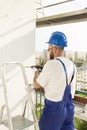 Worker in work attire, protective gloves and a helmet on site. Drilling the hole with a drill in the wall. Royalty Free Stock Photo