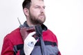 A worker in work clothes with a beard on his shoulder has an electric hammer