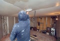 Worker is working with palette-knife for flattening the ceiling from wooden platform in room of apartment is inder Royalty Free Stock Photo