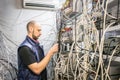 Worker works on the control panel in the data center. Specialist connects coaxial television wires in the rack of the TV station Royalty Free Stock Photo