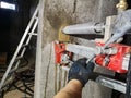 A worker works with a diamond drill on a machine fixed to the wall, drills a hole in the concrete for an electric cable and outlet Royalty Free Stock Photo