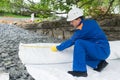 A worker in a workwear hides with a special cloth the bottom of an artificial lake, side view Royalty Free Stock Photo