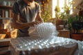 Worker wraps a valuable item in bubble wrap for secure shipment in a cozy, well-lit workspace.GenerativeAI. Royalty Free Stock Photo