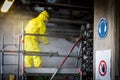 Worker in a yellow plastic overall is busy with high pressure cleaning a heat exchanger