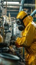 A worker in a yellow protective suit and gas mask checks for a chemical leak at a chemical factory