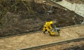 a worker in a yellow raincoat rams the sand