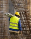 Worker in yeloow hard hat transmits the metal parts of the stru