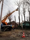 Workers on aerial work platform, on truck, prune tree branches among electricity lines in a village Ukraine. Pollarding process Royalty Free Stock Photo