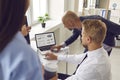 Workers analyze data statistics on a laptop by pointing to a screen displaying graphs and charts.