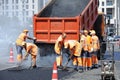 Workers asphalting repair the road on the street using shovels and dump truck