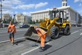 Workers asphalting repair the road on the street using shovels and front loader