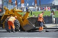 Workers asphalting repair the road on the street using shovels and front loader