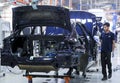 Workers assembles cars at automobile assembly line production plant