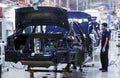 Workers assembles cars at automobile assembly line production plant