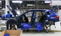 Workers assembles cars at automobile assembly line production plant