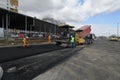 Workers behind a track asphalt paver machine