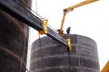 workers building a large fuel tank during a snowstorm