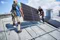 Workers building solar panel system on roof of house. Installers carrying photovoltaic solar module Royalty Free Stock Photo