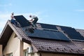 Workers building solar panel system on roof of house. Installers carrying photovoltaic solar module Royalty Free Stock Photo