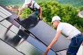 Workers building solar panel system on roof of house. Men installing photovoltaic solar module Royalty Free Stock Photo