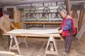 Workers in carpentry line up glued wooden profiles before pressing in the large clamp machine