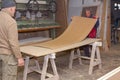 Workers in carpentry line up glued wooden profiles before pressing in the large clamp machine