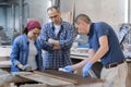 Workers in carpentry woodworking workshop, varnishing wooden plank with oil