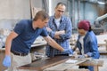 Workers in carpentry woodworking workshop, varnishing wooden plank with oil