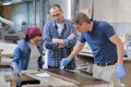 Workers in carpentry woodworking workshop, varnishing wooden plank with oil