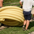 Workers carry a roll of yellow drainage pipe in their hands. Preparation for drainage works.