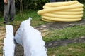 Workers carry a roll of yellow drainage pipe in their hands. Preparation for drainage works.