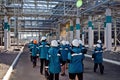 Workers of chemical factory in working clothes walks near large pipeline construction to their workplaces